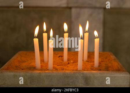 Goiânia, Goias, Brazil – November 12, 2022: Several lighted candles in a sand holder in the church. Candles lit in the temple, holy fire. Stock Photo