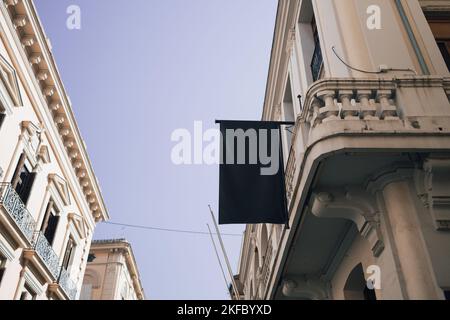 empty blank black banner for advertisement mounted on grey fence of construction site at city street outside mock-up. Stock Photo