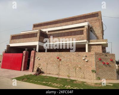 old style bricks house with red gate , bricks made building, house made finished with bricks and white paint and red gate Stock Photo