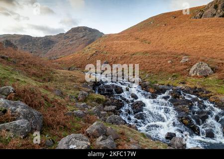 A waterfall coming from Easedale Tarn with Tarn Crag hill in the background Stock Photo