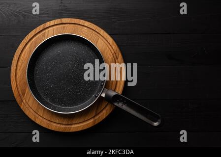 Empty pan on wood board. Empty marble coated iron pot Stock Photo