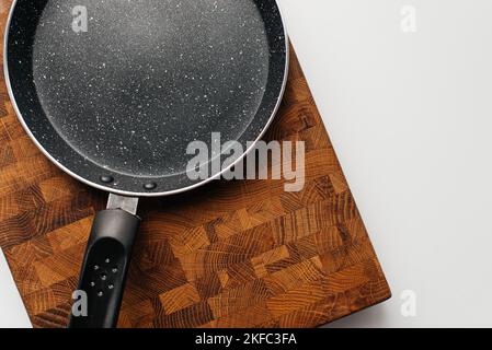 Empty pan on wood board. Empty marble coated iron pot Stock Photo