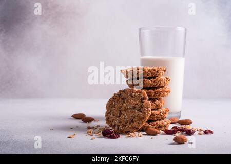 Granola energy biscuits or cookies with cereals, almond nuts and glass of milk for healthy nutrition on grey concrete background Stock Photo