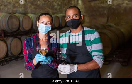 Specialists in protective mask checking ageing process of wine Stock Photo