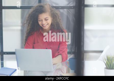 Portrait of Young Successful Caucasian Businesswoman Sitting at Desk Working on Laptop Computer in City Office Stock Photo