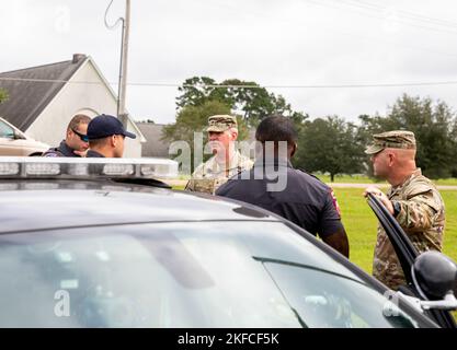 Brig. Gen. John Nipp (center), commander of the 184th Sustainment Command, Mississippi Army National Guard, speaks with Mississippi Highway Patrol troopers at Davis Road Park near Jackson, Mississippi, Sept. 7, 2022. Over 11,000 cars received bottled water, hand sanitizer and non-potable water from water buffalo trucks since the site opened Sept. 1. Stock Photo