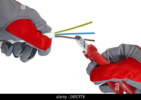 An electrician cuts a three-core copper wire with wire cutters Stock Photo