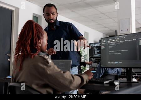 African american engineers typing machine learning html code on computer, sitting at desk table in big data office. Software developers working on database system with html script in it security agency. Stock Photo