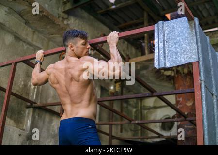 A strong muscular man doing pull ups outdoors Stock Photo