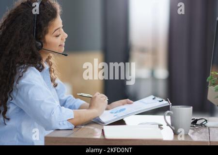 Side view of cheerful operator in headset in office Stock Photo