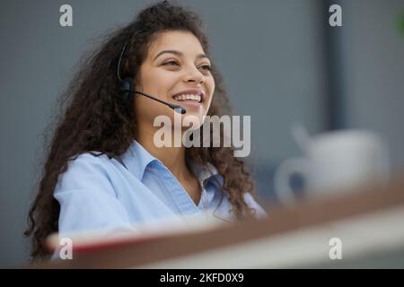 Brunette business woman using headset to communicate and advise people in customer service office. Call centre. Stock Photo