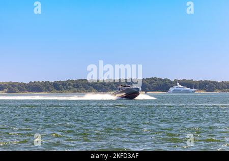 motor boat underway with a large yacht in the distance Stock Photo