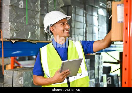 Smart Asian foreman or warehouse worker is working in a warehouse, using tablet, checking and managing inventory to prepare for shipping. shipping and Stock Photo