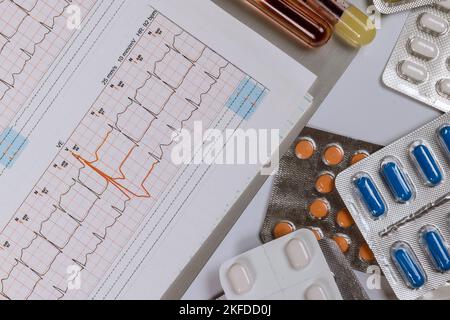 On table several different pills doctor examines cardiogram in medical office. Stock Photo