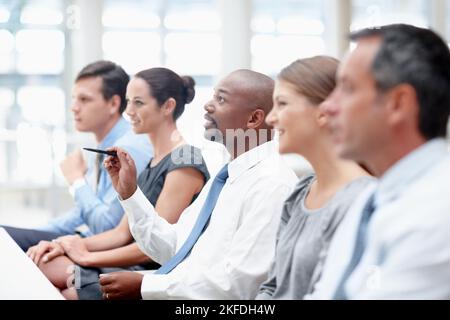 Learning their way to success - Business conference. Interested team of executives sit in a meeting together. Stock Photo