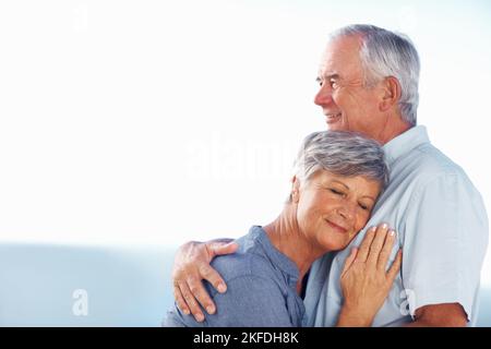 Loving mature couple spending time outdoors. Mature woman resting head on mans chest while spending time outdoors. Stock Photo