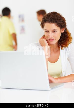 Business woman using laptop. Business woman using laptop with colleagues in background. Stock Photo