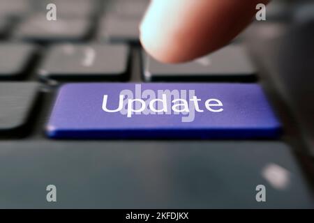 Customized concept with computer enter button on keyboard: Update. A male finger presses a color button on a keyboard of a modern laptop. Button with Stock Photo