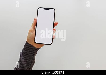 Female hand holding a modern smart phone with a white screen, mobile phone mock-up Stock Photo