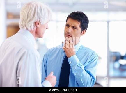 Clearing doubts. Portrait of doubtful business man listening to senior executive at office. Stock Photo