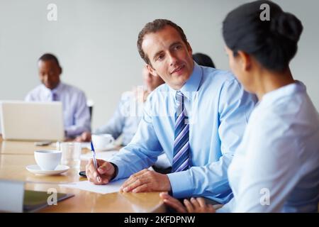 Executives having a quick discussion. Two executives conversing in board room with rest of executives. Stock Photo