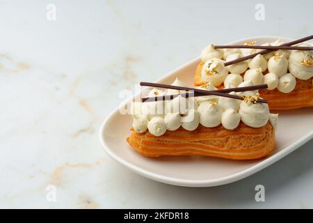 Two eclairs with white custard on whhite plate Stock Photo