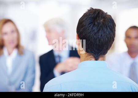 Job seeker. Rear view of young applicant getting interviewed by panel. Stock Photo