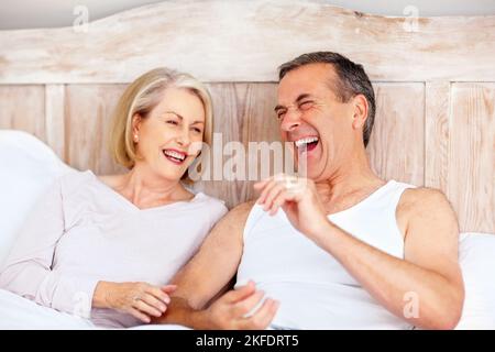 Cheerful mature couple having fun in bed. Portrait of a cheerful mature couple having fun in bed. Stock Photo