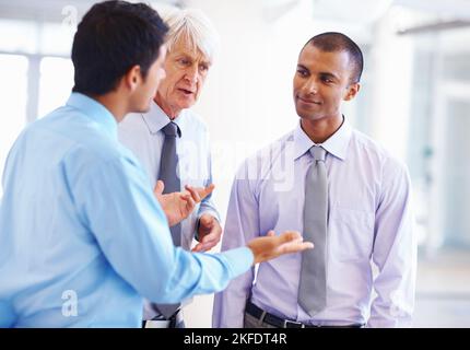 Executive listening to other professionals. Portrait of African American executive listening to other male professionals. Stock Photo