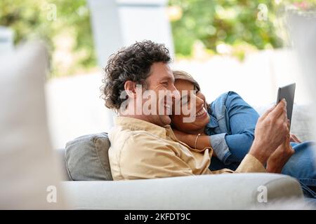 Quality time online. a husband and wife using a digital tablet together at home. Stock Photo
