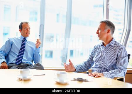 Partners in casual meeting over coffee. Partners having casual meeting indoors at table. Stock Photo