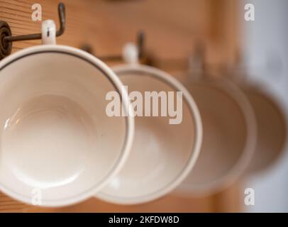Cups hanging in a row on a wooden shelf Stock Photo