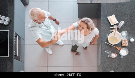 Top view dancing and senior couple in kitchen having fun, bonding and enjoy retirement together. Love, romance and aerial of happy elderly man and Stock Photo