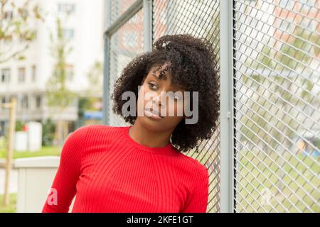 pensive african american young woman leaning on a fence Stock Photo