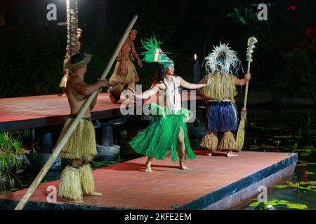 A nighttime island dance show in Rarotonga, Cook Islands. A female dancer in a traditional headdress performs on a raft Stock Photo