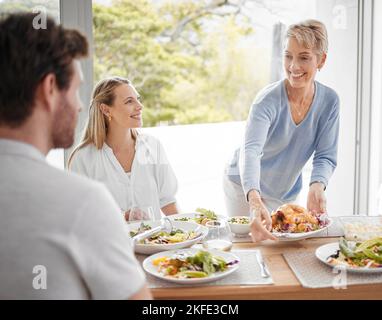 Family, lunch and food for dining, meal and happy at table for celebration event, eating and happiness together. Hosting, family home and thanksgiving Stock Photo