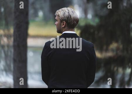 Rear view of well-build fit handsome blond Scandinavian man waiting for his bride. Outdoor forest autumn photoshoot. Marriage and life together. High quality photo Stock Photo