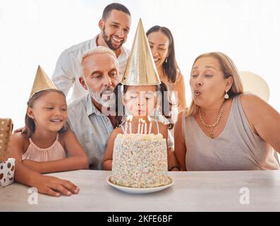 Children birthday party, birthday cake or candles for blowing out with mother, father and senior grandparents in home. Fun, excited or happy kids and Stock Photo