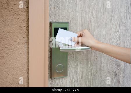 Hand holding key card scanning to unlock wooden door at resort. Digital door scanner access control security system Stock Photo