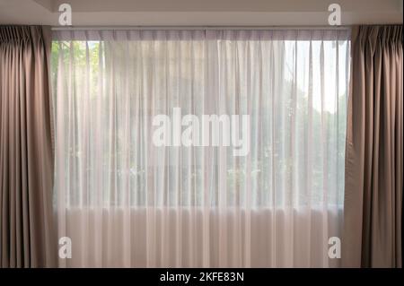 Open beige curtain with light filter fabric on window at home Stock Photo