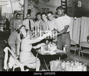 Crew members of the USS Lake Champlain (CVA-39) participating in the ship's two day blood drive, with the crew pledging to make a quota of 1000 pints, 20604. Stock Photo