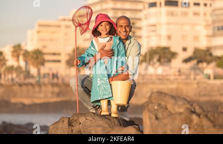 Father, daughter and fishing portrait with a man and child on a ocean holiday for bonding with love. Fish, net and bucket with a dad and girl kid Stock Photo