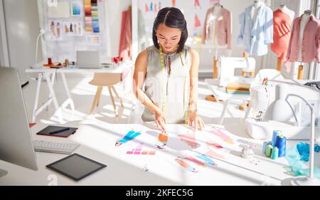 Designer, woman and choice of sample for fashion, style and design in studio for label, brand or collection. Creative asian woman, lookbook or cutout Stock Photo