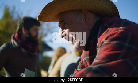 Senior happy farmer selling fruits and vegetables at the stall, talking ...