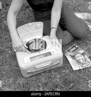 How a combined portable radio and record player looked in the 1960s. A gramophone player as it looked at this time.  This model was battery operated and could play singles,  7 inches 45 rpm vinyl records. You could also listen to the radio on it's radio function, turning the knobs to the frequency and station you wanted to listen to. A practical lid is seen opened and when not using the gramophone you closed it.  Sweden 1960 Conard ref 4264 Stock Photo