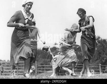 In the 1930s. A group of women are competing in moving quickly and balancing potatoes at the same time. The goal was to go through the track as fast as possible without dropping a potatoe. The event took place on 4th of July, the Independence day of USA. Sweden 1938 Stock Photo