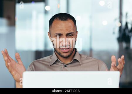 Upset businessman close up looking at laptop screen at work, man unhappy with received email notification, employee disappointed with work result inside office. Stock Photo