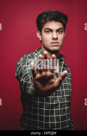 Indian Man Using Stop Gesture – Warning Against AI Threats and Cyber Crime. An Indian man is depicted with his palm wide open in a strong stop gesture Stock Photo