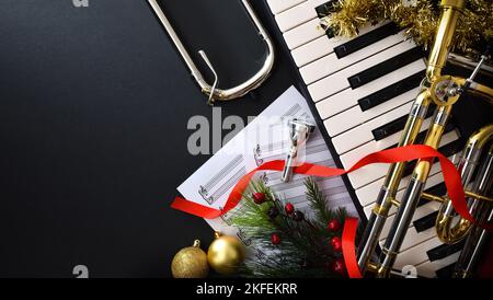 Christmas musical performance background with piano and trombone with christmas decoration, slider and mouthpiece. Top view. Stock Photo