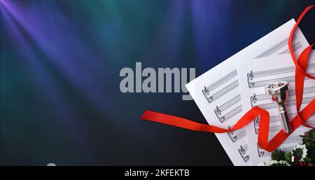 Christmas performance of brass instruments background with mouthpiece and sheet music on black table with colored lights. Top view. Stock Photo